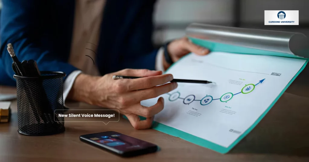 A person in business attire points at a colorful growth chart on a document. A phone with a New Silent Voice Message! notification is on the desk, next to a pen holder. The Carnegie University logo is in the top right corner. VoiceDrop Ringless Voicemails