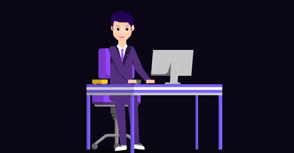 A smiling person in a purple suit sits at a desk with a computer monitor and a yellow book, perhaps reviewing telemarketing strategies, on a purple office chair against a dark background. VoiceDrop Ringless Voicemails