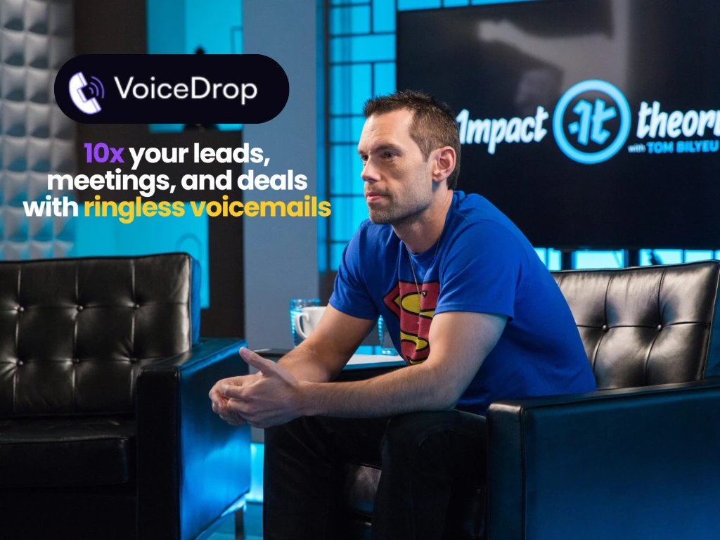 A man in a Superman t-shirt sits on a black couch in a studio. Text on the image reads, VoiceDrop: 10x your leads, meetings, and deals with ringless voicemails. A wall displays Impact Theory with Tim Bilyeu. VoiceDrop Ringless Voicemails