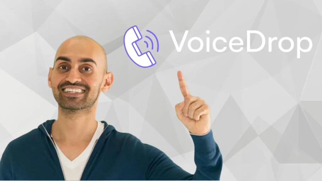A smiling man with a shaved head and beard points upward toward the VoiceDrop logo, which features a stylized purple phone icon, on a light geometric background-perfect for those looking to scale your business with ringless voicemail. VoiceDrop Ringless Voicemails