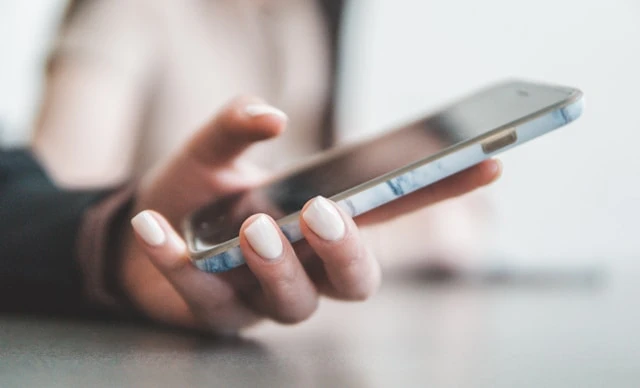 A person holding a smartphone with focus on the hand and the phone, demonstrating a modern and connected lifestyle through the use of ringless voicemail technology.